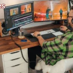 a person sitting at a desk with two monitors yomovies